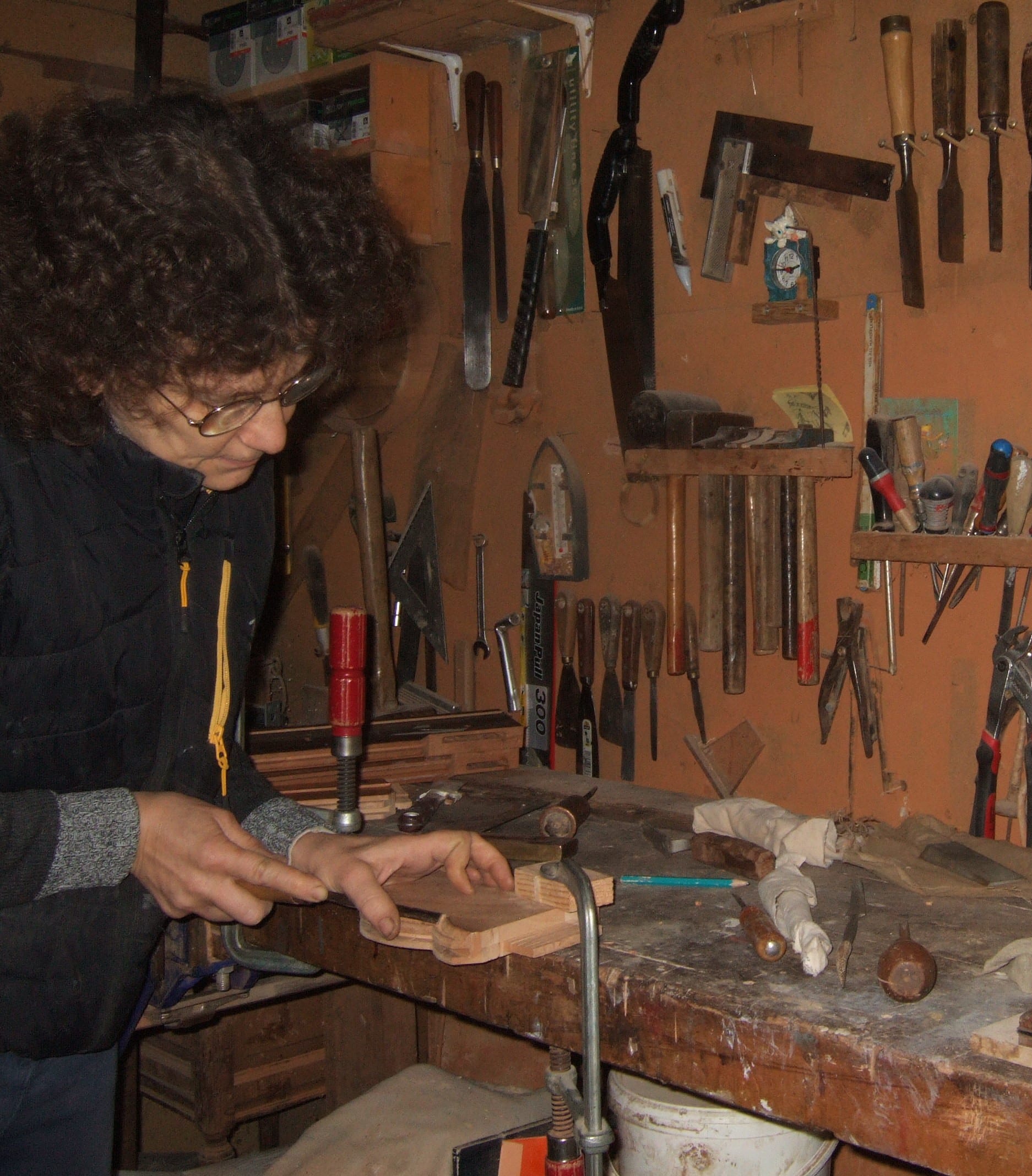 Ébéniste au travail à l'établi, entourée de ses outils traditionnels